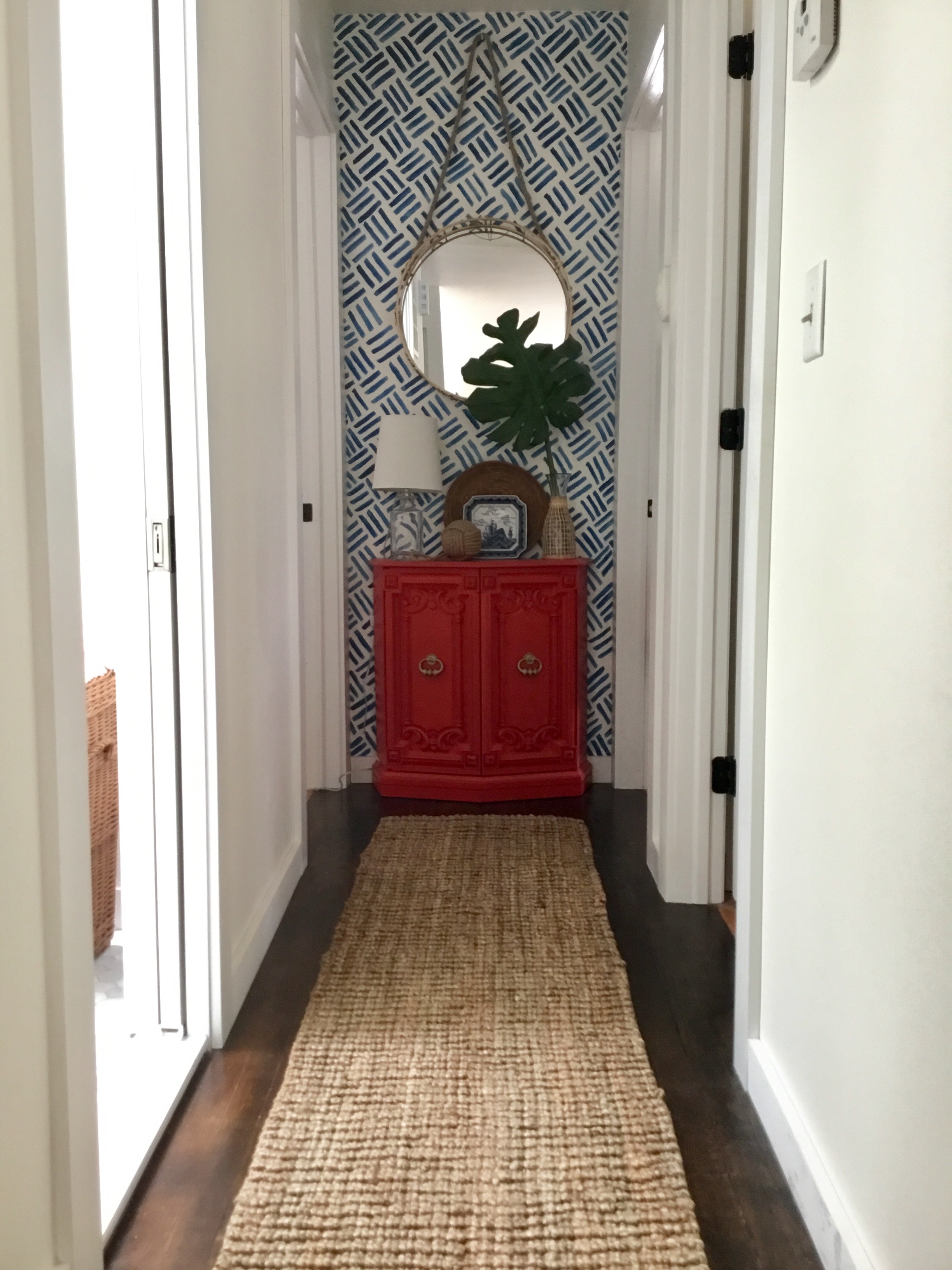 Hallway with hand painted blue and white accent wall, jute runner, coral stand with mirror and lamp