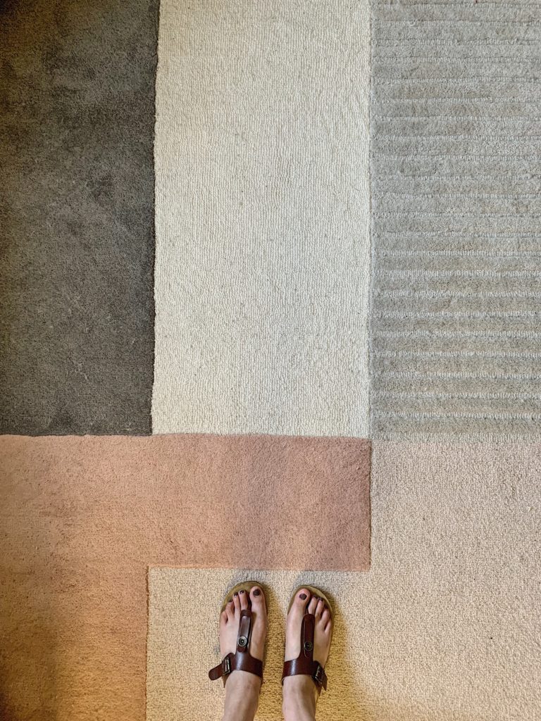 62 color blocked rug in gray, cream and blush with woman’s feet wearing sandals.