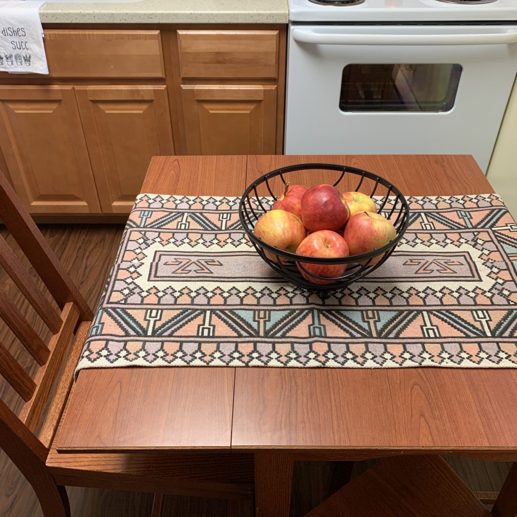 table runner made from five below rug on small table with bowl of apples