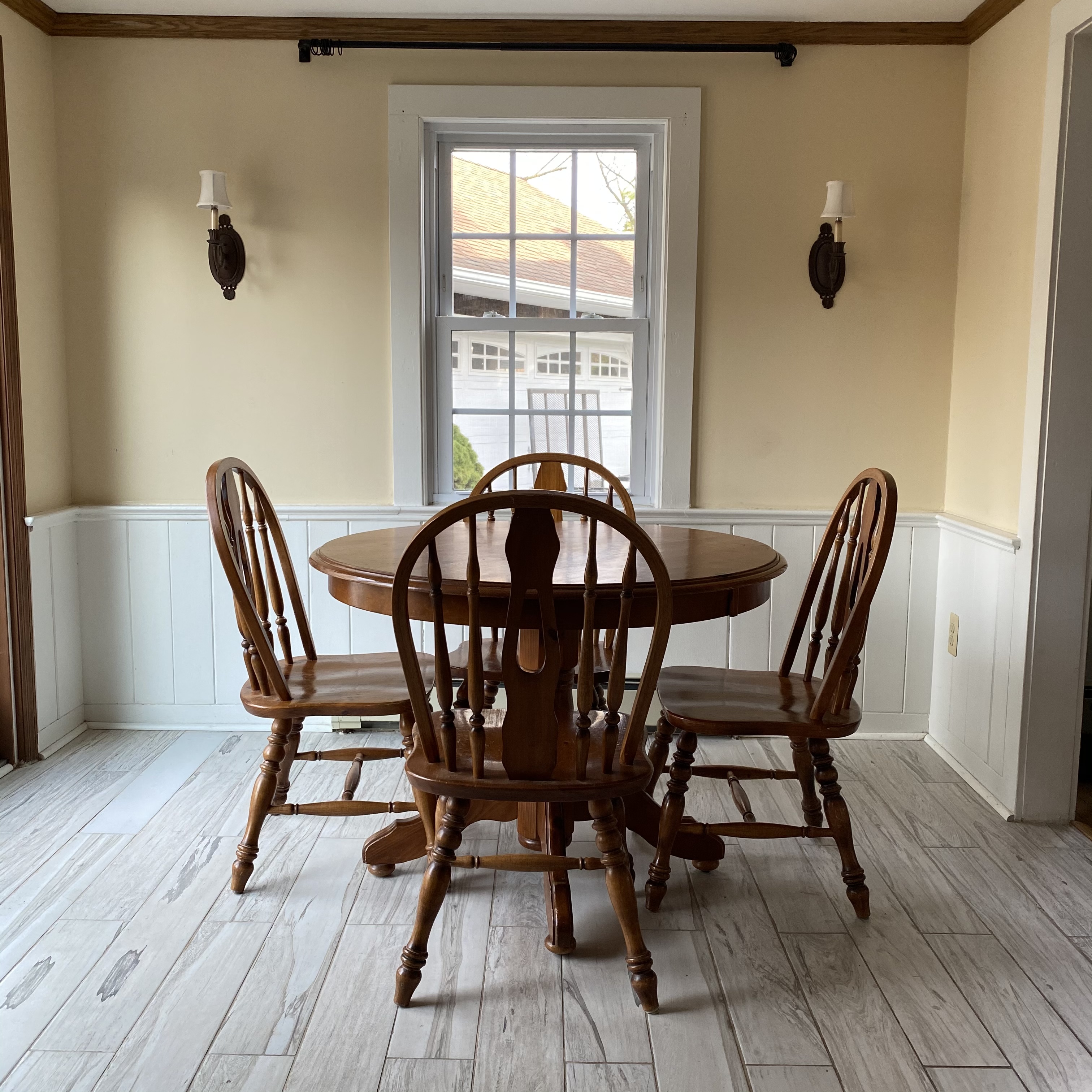 kitchen with stained wood table and chairs, white window and whitewashed floor