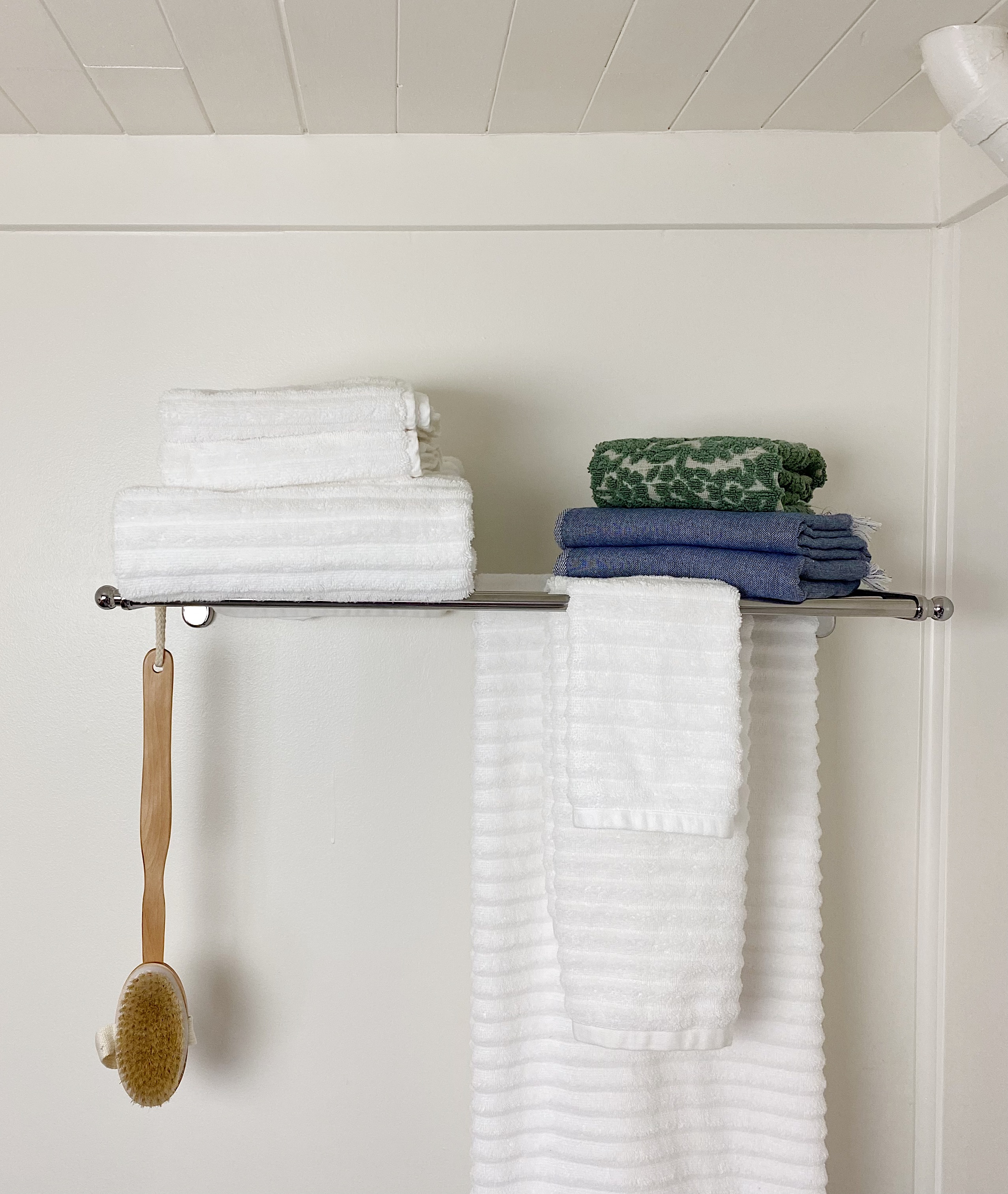 chrome shelf with towels on wall