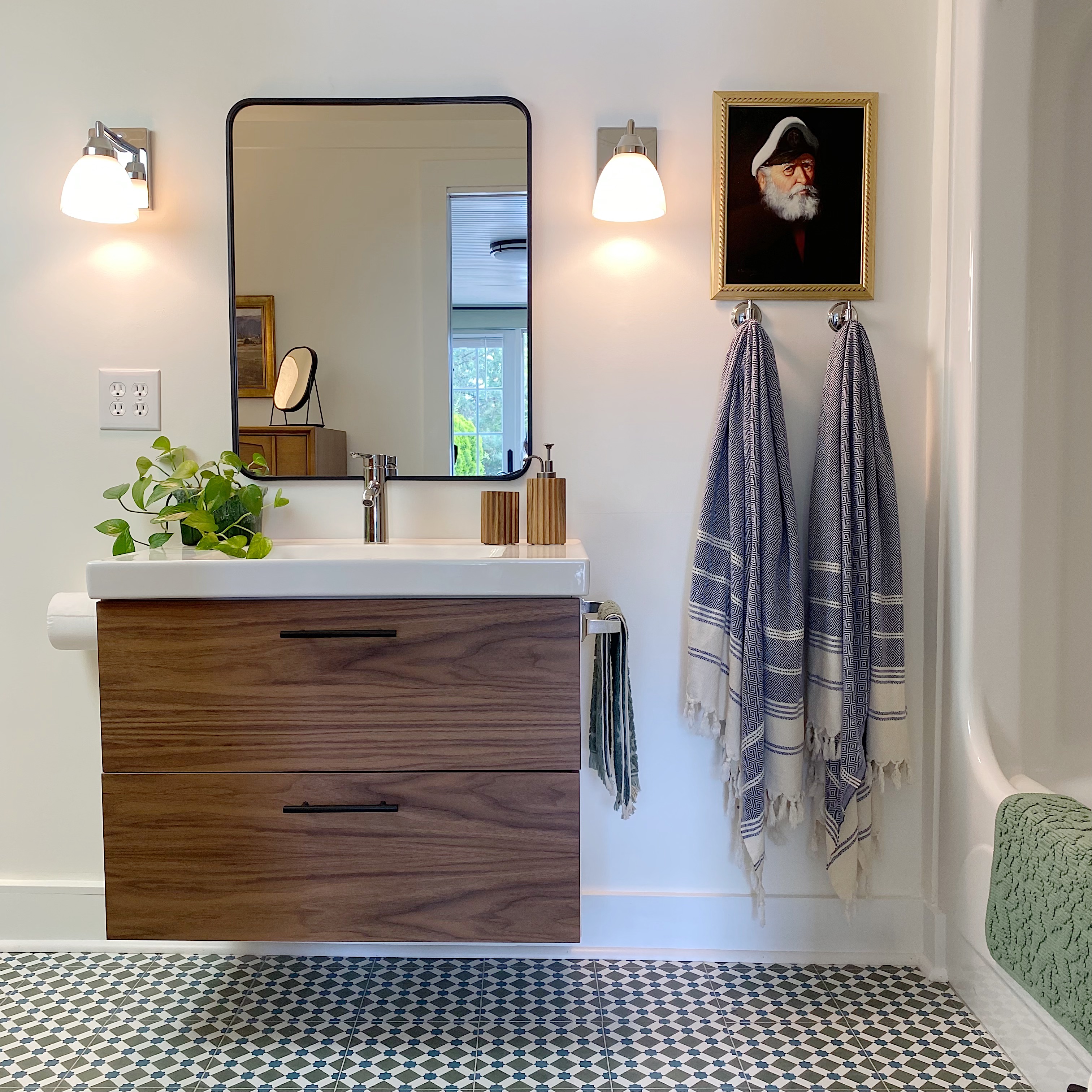 white bathroom with patterned floor tile, Ikea vanity with wood drawer fronts and black framed mirror