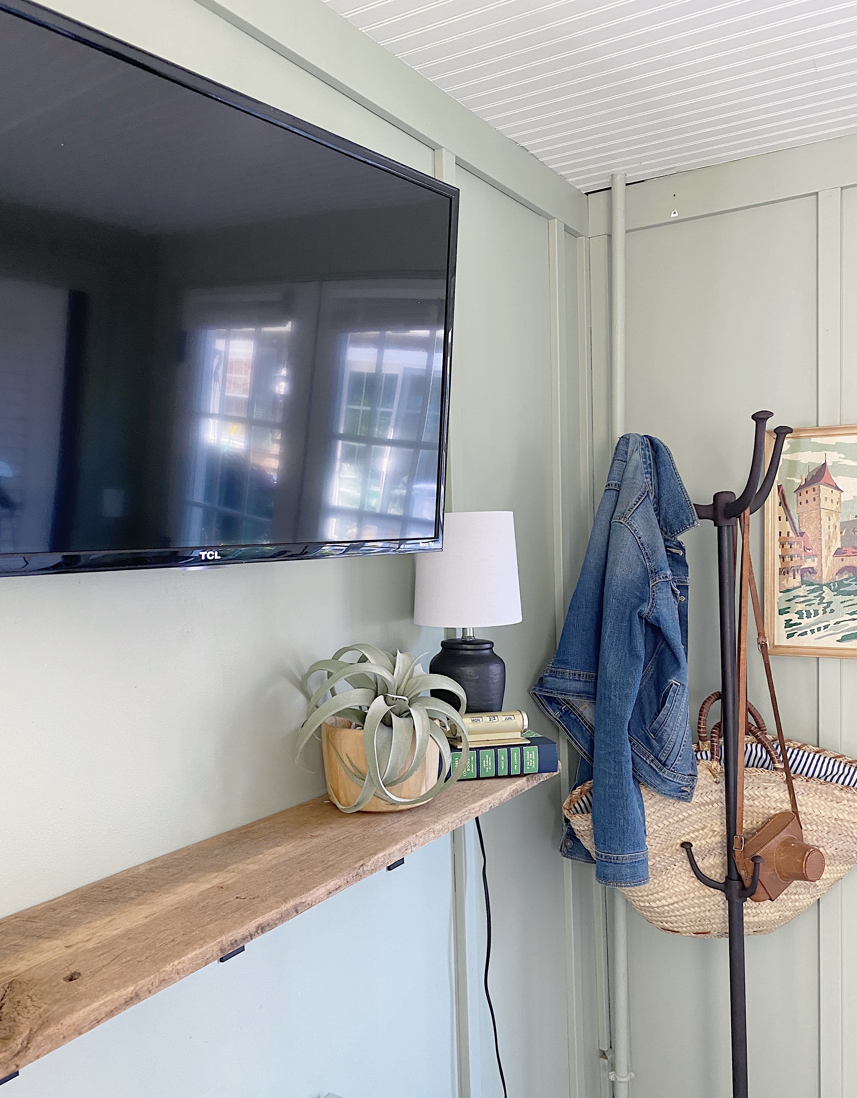wall mounted tv with vintage wood plank shelf, small lamp and pottery barn coat tree