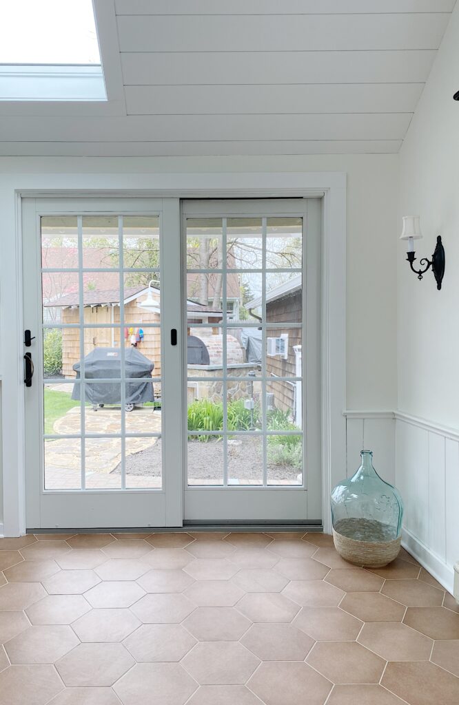 White patio door with shiplap ceiling and terracotta floor tile