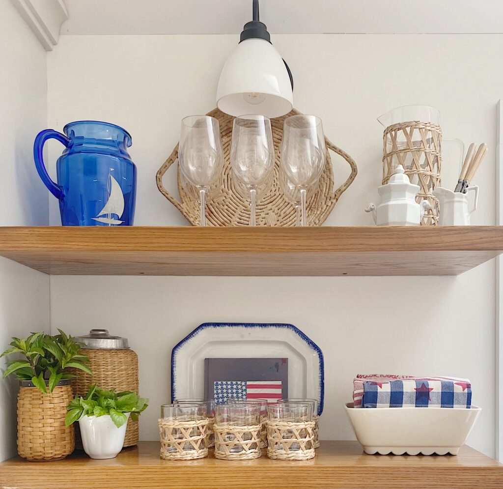 Oak open shelves in kitchen styled with red white and blue dishes and towels